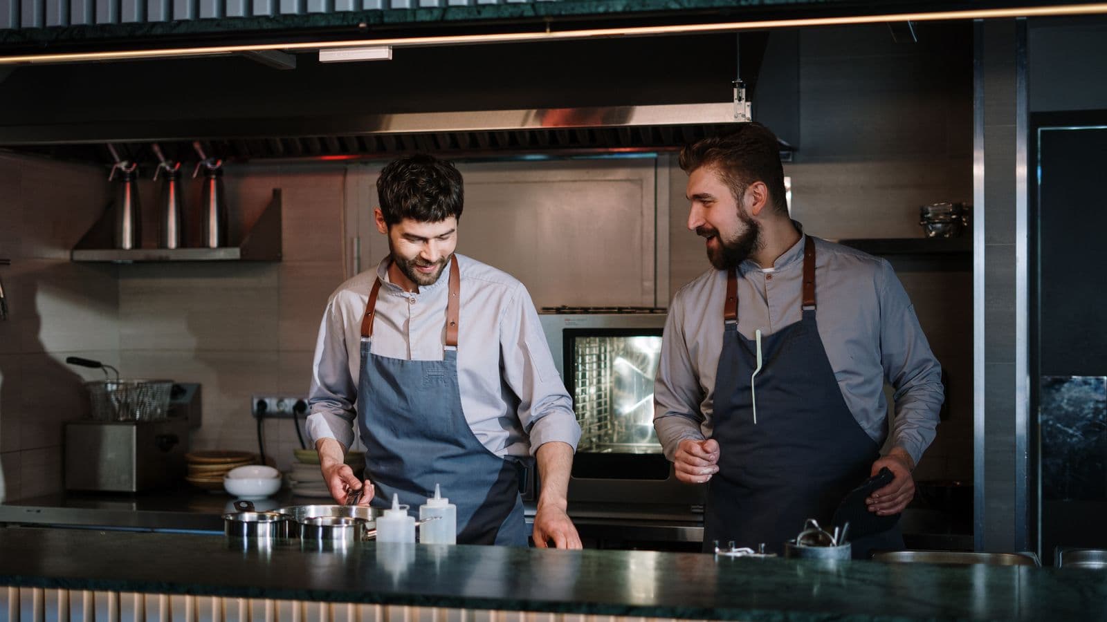 Deux cuisiniers dressent des assiettes dans une cuisine ouverte
