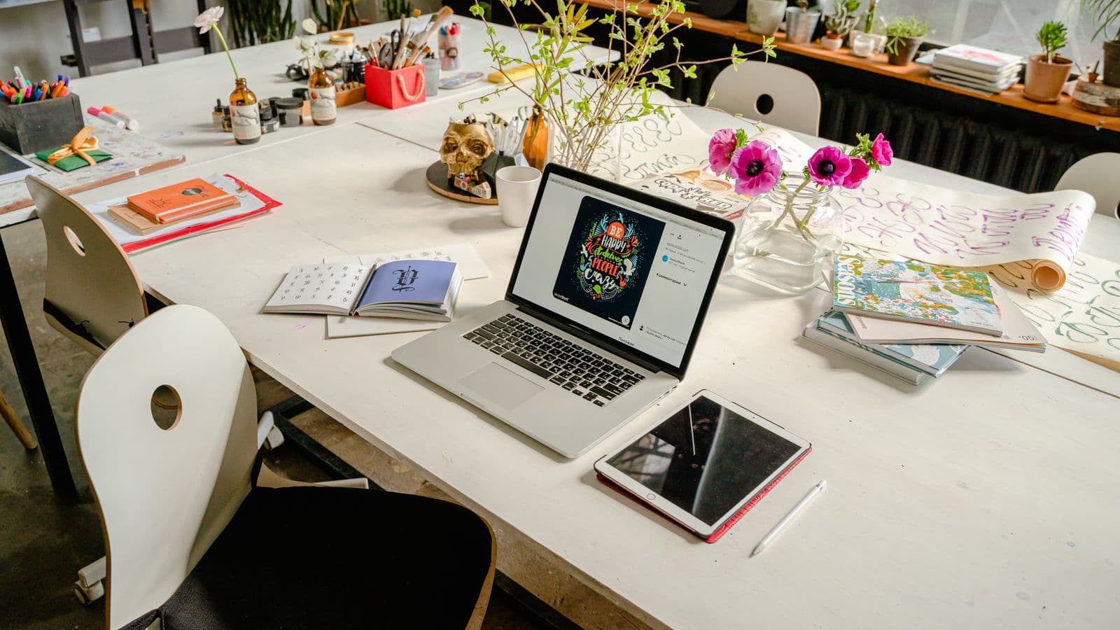 La grande table de travail d'un studio de design, avec un ordinateur portable